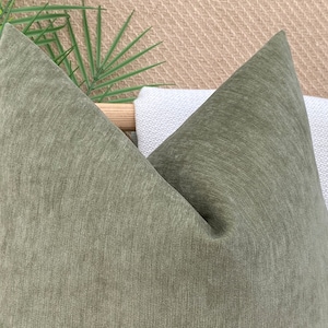 May include: A green, textured throw pillow with a pointed shape. The pillow is made of a soft, woven fabric.