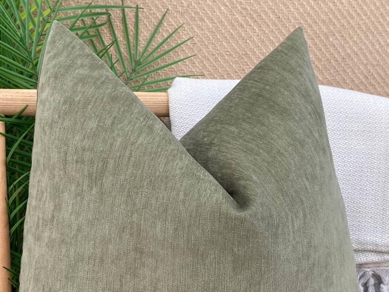 May include: A green, textured throw pillow with a pointed shape. The pillow is made of a soft, woven fabric.