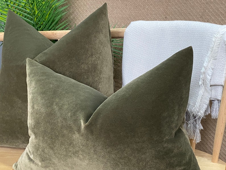 May include: Two green velvet throw cushions with a textured surface.
