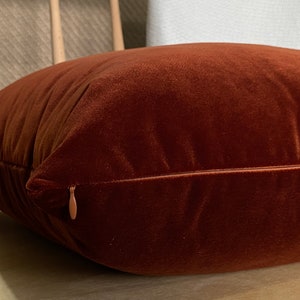 Peut inclure: Gros plan sur un coussin en velours rouille avec une fermeture &eacute;clair.