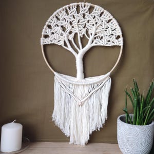 Peut inclure: Suspension murale en macramé blanc en forme d'arbre avec un cercle en bois et des franges.