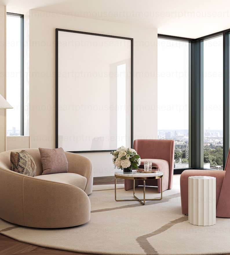 May include: A modern living room with a large, empty picture frame, a curved beige sofa, two pink armchairs, a white side table, a coffee table with a marble top, and a bouquet of white flowers.
