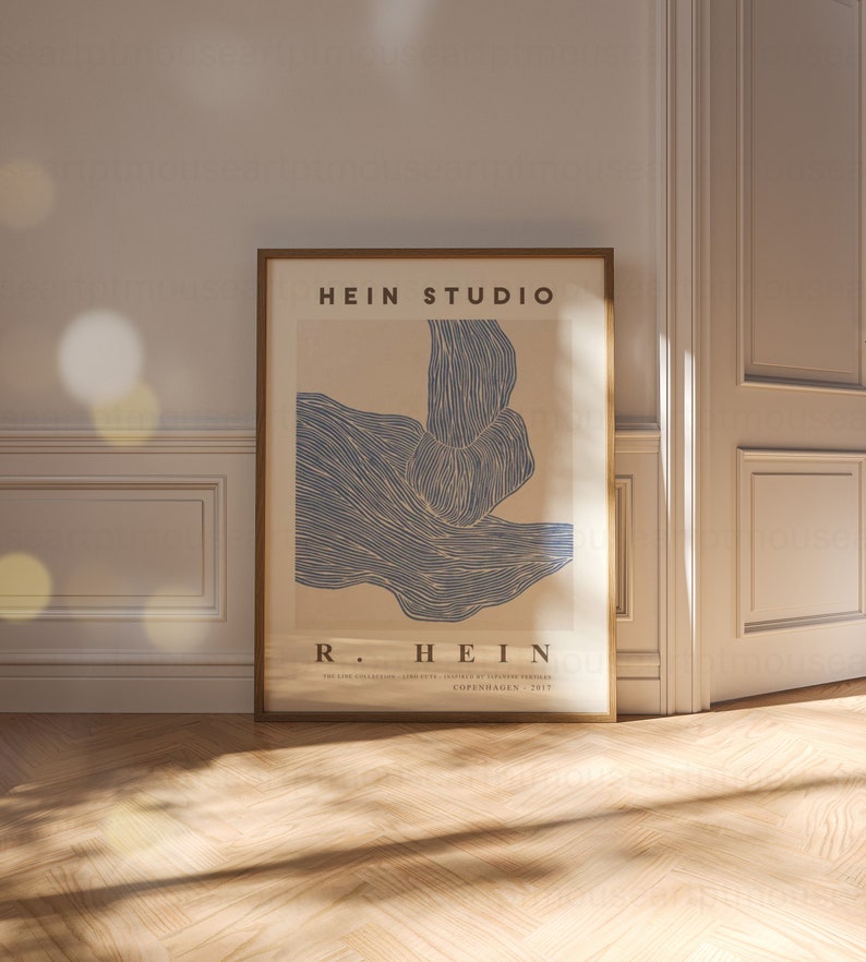 May include: A framed poster with a blue abstract design and the text "HEIN STUDIO" and "R. HEIN" in a brown frame. The poster has the text "THE LINE COLLECTION - LEISURE CITY - PRINTED BY OLIVER PRESSES - COPENHAGEN - 2017".