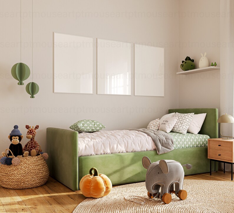 May include: A green upholstered daybed with a white and green patterned duvet and pillows. There are two framed pictures on the wall behind the bed. A wicker basket with stuffed animals sits on the floor next to the bed. A gray elephant toy with wooden wheels sits on a rug in front of the bed.