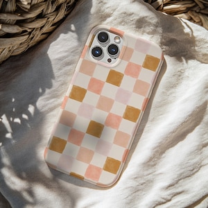May include: A phone case with a watercolor checkerboard pattern in shades of peach, pink, and gold. The case is on a white background and has a camera lens cutout.