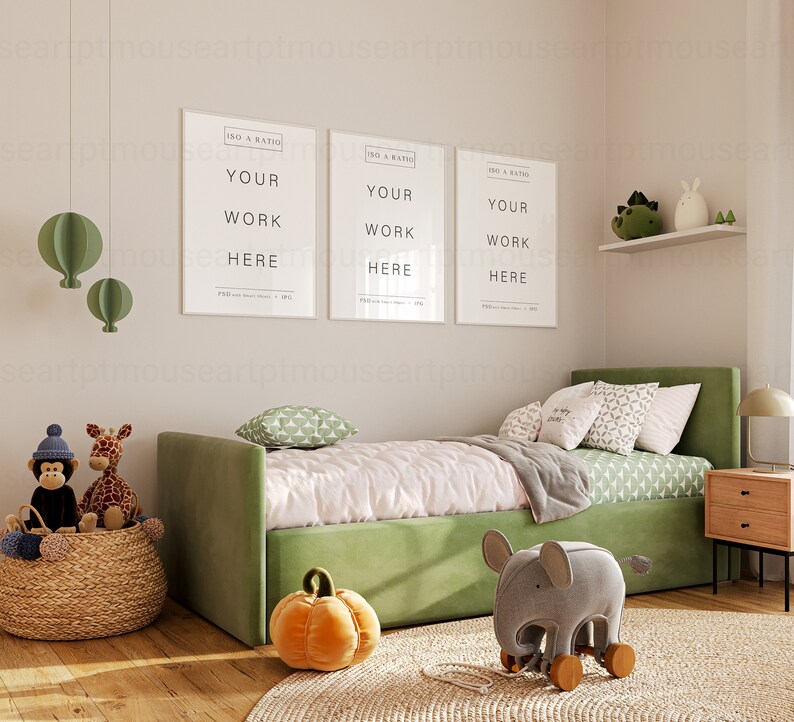 May include: A green daybed with white bedding and green pillows. There are three framed posters above the bed that say "Your Work Here". There are stuffed animals on the bed and a wooden elephant toy on the floor.