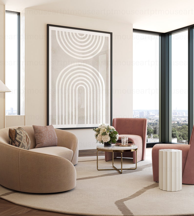 May include: A living room with a curved beige sofa, two pink armchairs, a white side table, a coffee table with a white marble top and gold legs, and a framed abstract print with white lines on a beige background.