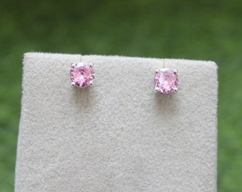 Pode incluir: Um par de brincos de prata com pedras redondas cor-de-rosa.