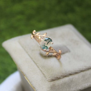 May include: A gold ring featuring a green moss agate stone set within a delicate vine design.