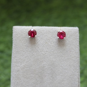 Può includere: Un paio di orecchini a lobo d'argento con pietre rotonde rosse.