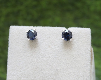 May include: A pair of silver stud earrings with dark blue round gemstones.