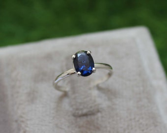 Op de afbeelding: Een zilveren ring met een donkerblauwe ovale edelsteen.