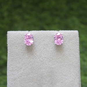 May include: A pair of silver stud earrings with oval-shaped pink gemstones.