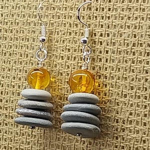 May include: A pair of earrings with a stack of gray stones and a yellow amber bead on each earring.