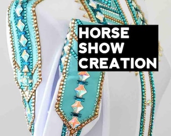 May include: White horse show shirt with turquoise and gold embellishments. The shirt has a collar and long sleeves. The embellishments are made of rhinestones and beads. The text "HORSE SHOW CREATION" is printed on a black rectangle in the center of the image.