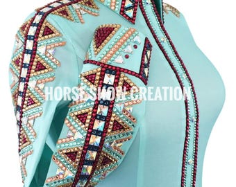 May include: A light blue show shirt with intricate beadwork and rhinestones. The shirt features geometric patterns in red, gold, and turquoise. The text "HORSE SHOW CREATION" is visible on the front.