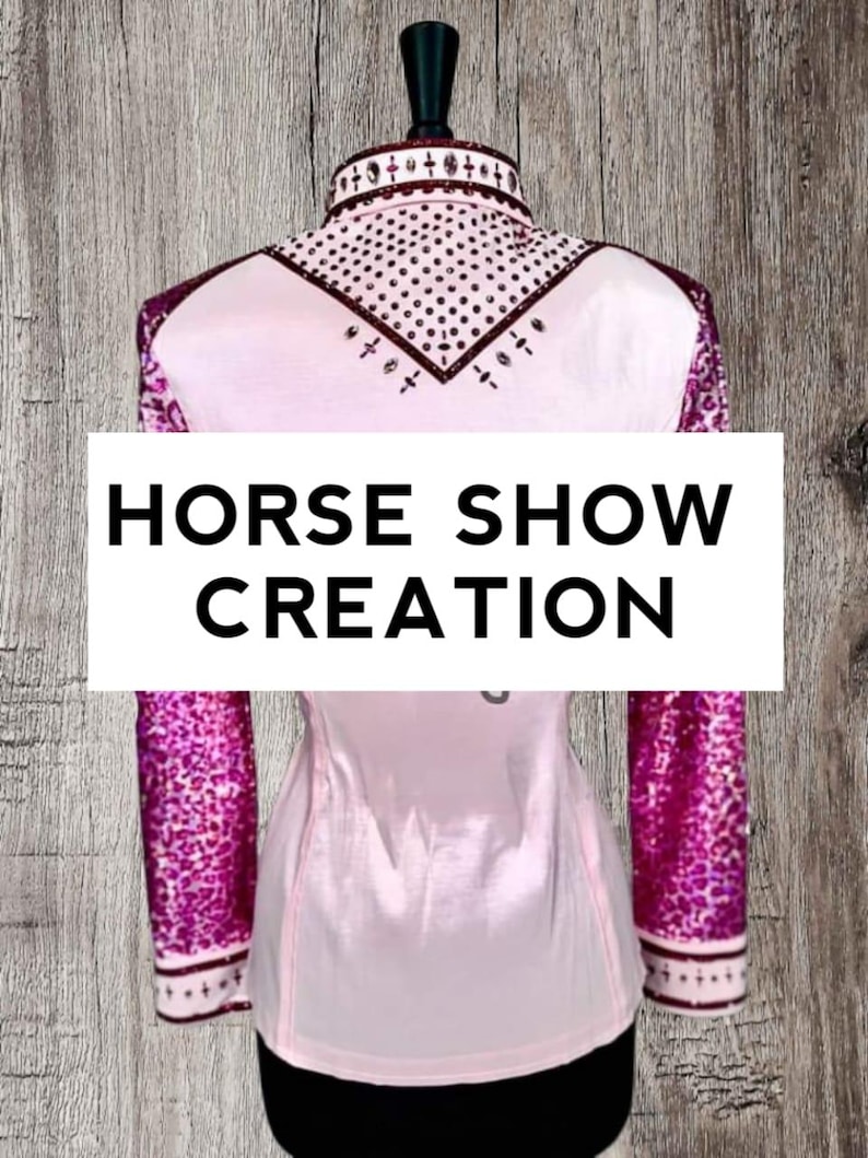 May include: Pink horse show shirt with a maroon collar and sleeves. The sleeves have a pink and maroon patterned design. The collar has rhinestones and a maroon trim. The shirt says "HORSE SHOW CREATION" on the front.