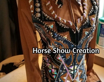 May include: A brown show shirt with a black and blue vest featuring rhinestones and a geometric design. The shirt has a zipper closure and a collar. The text "Horse Show Creation" is visible on the shirt.