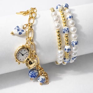 May include: Gold-toned charm bracelet with a heart-shaped charm, a miniature clock, and blue and white porcelain beads.  Also, three pearl bracelets with gold accents and blue floral beads.  Jewelry.