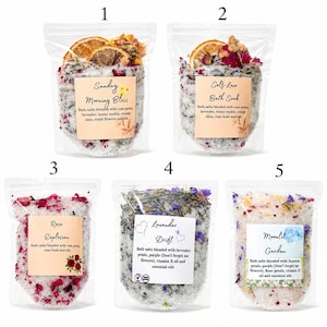 Puede incluir: Cinco bolsas transparentes de sales de ba&ntilde;o numeradas del 1 al 5. Las etiquetas indican Sunday Morning Bliss, Self-Love Bath Soak, Rose Explosion, Lavender Drift y Moonlit Garden. Cada bolsa contiene sal, flores secas y rodajas de fruta.