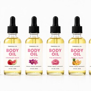 May include: Six clear glass dropper bottles of body oil, each containing 2 fl oz of golden liquid. The white labels feature the text PINKSOULL CO. BODY OIL, specific scent names like Vanilla, Strawberry Melon, Love Spell, Pink Bombshell, Tropical Melon, and Watermelon, and the volume 2 FL OZ | 59 ML.
