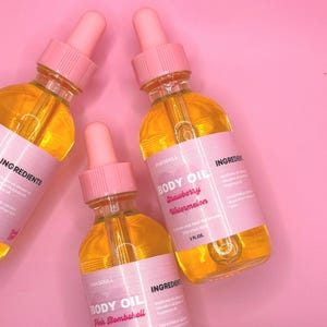 May include: Three clear glass bottles of body oil with pink labels and droppers. The labels read "BODY OIL" and "PINKSOULL", with the flavors "Pink Bombshell" and "Strawberry Watermelon". Each bottle contains 2 fl oz of oil.