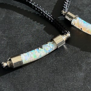 May include: Two black cord necklaces with silver caps and clear tubes filled with iridescent opal chips.