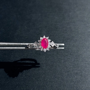 Può includere: Un anello d'argento con una grande pietra preziosa rosa ovale circondata da piccole pietre preziose chiare.