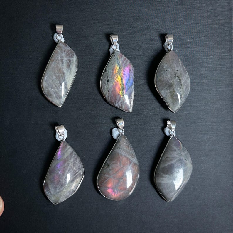 Pu&ograve; includere: Sei ciondoli con pietre preziose con bails color argento. I ciondoli hanno varie forme, tra cui a goccia e irregolari. Le pietre mostrano una gamma di colori, tra cui grigio, viola e lampi iridescenti.