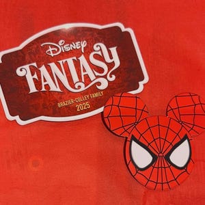 May include: A red Spider-Man-themed Mickey Mouse head-shaped design with a web pattern and white eye details. Next to it is a maroon and white Disney Fantasy sticker with the text "BRAZIER-COLLEY FAMILY 2025" on a red background.