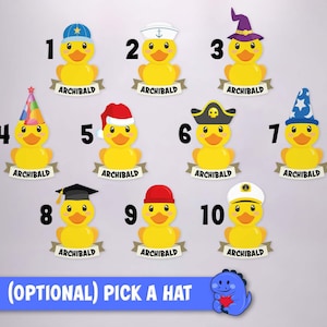 May include: Ten yellow rubber ducks arranged in rows, each wearing a different hat and featuring a banner below with the name ARCHIBALD. The hats include a baseball cap, sailor hat, wizard hat, party hat, Santa hat, pirate hat, and graduation cap.