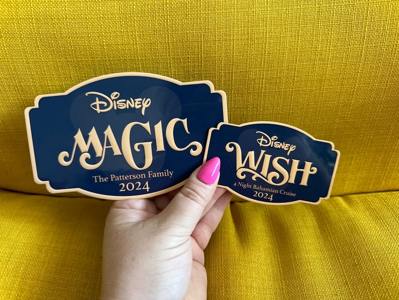 May include: Two navy blue Disney cruise signs. One says "MAGIC" with "The Patterson Family 2024". The other says "WISH" with "4 Night Bahamian Cruise 2024". Both have a cream-colored font.