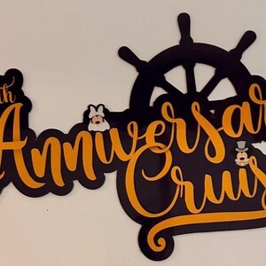 Op de afbeelding: Een zwart en oranje bord met de tekst 40th Anniversary Cruise in een gestileerd scriptlettertype. Het ontwerp bevat een zwart icoon van een scheepsroer en twee kleine stripfiguurhoofdjes die tussen de woorden zijn geplaatst.