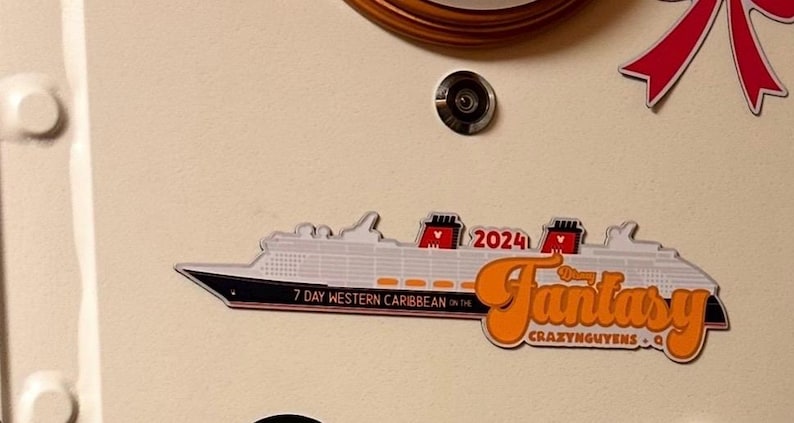 May include: A white and black cruise ship magnet with the word "Fantasy" in orange script. The magnet also includes the text "7 Day Western Caribbean" and "2024". The background is a light beige color.