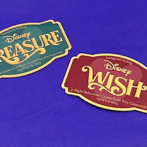 May include: Two rectangular Disney cruise magnets. One is teal with "TREASURE" in gold script. The other is maroon with "WISH" in gold script. Both have cruise details and dates.