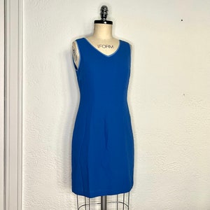 May include: A sleeveless blue dress with a light blue trim around the neckline. The dress is fitted and has a straight skirt.