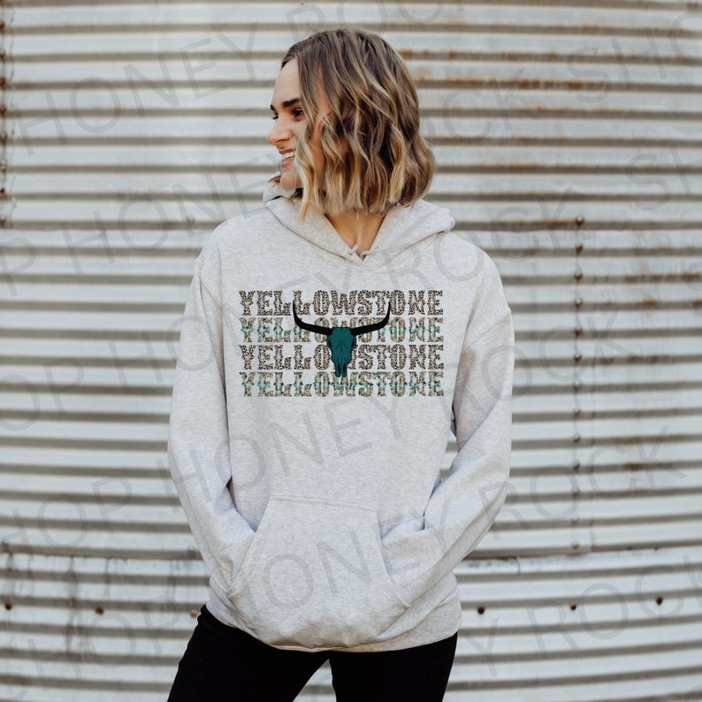 May include: A gray hoodie with a teal and black bull skull graphic and the text "Yellowstone" repeated four times.