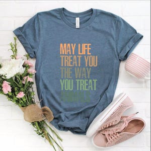 May include: A blue t-shirt with the text "May life treat you the way you treat animals" printed in a rainbow gradient.