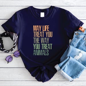 May include: A navy blue t-shirt with a vintage-style graphic that reads "May life treat you the way you treat animals".