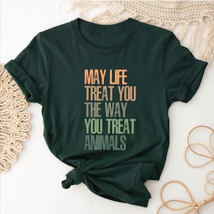 May include: A dark green t-shirt with the text "May life treat you the way you treat animals" printed in a rainbow gradient.