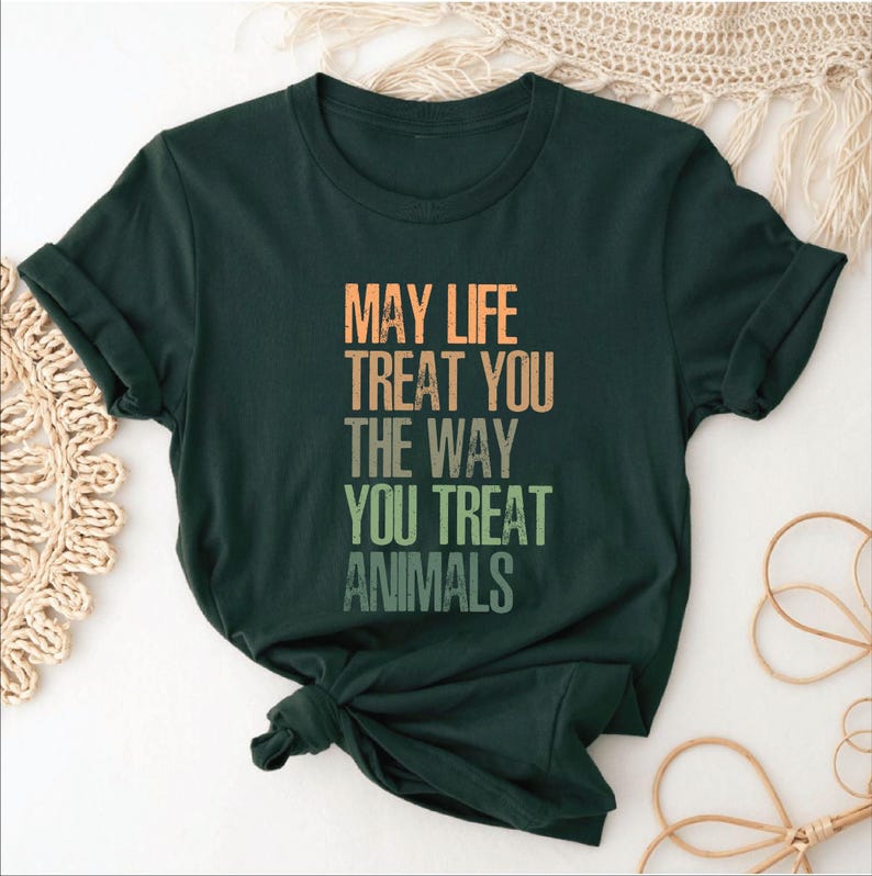 May include: A dark green t-shirt with the text "May life treat you the way you treat animals" printed in a rainbow gradient.