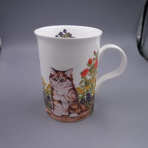 以下が含まれることがあります： 白いセラミックマグカップ。ふわふわの茶色とタン色の猫とカラフルな花の繊細なイラストが特徴です。 マグカップには湾曲したハンドルと、縁の内側に花の模様があります。 猫好きのコレクションに加えるのに最適です。