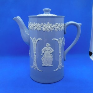 May include: A blue and white ceramic teapot with a white floral design and a white figure in the center.