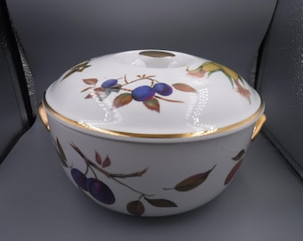 May include: White ceramic serving bowl with lid, featuring a gold rim and handles. The bowl is decorated with a plum and leaf design in shades of purple, brown, and green. The lid has a small gold accent.