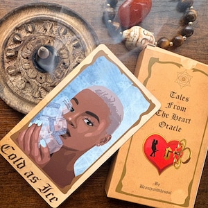 May include: A Tales From The Heart Oracle deck with a Cold as Ice card featuring an illustration of a person holding ice cubes. The set includes a tan box with a red heart and key graphic, a wooden incense burner with a smoking cone, and a beaded bracelet.