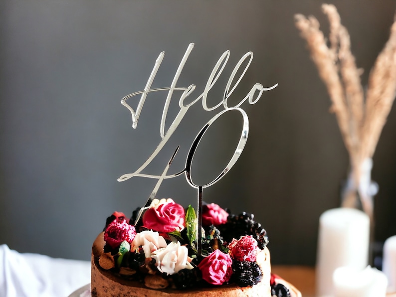 May include: A two-tiered cake decorated with red, pink, and white flowers, blackberries, and a silver cake topper that says "Hello 40".