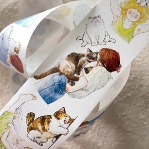 May include: Decorative washi tape featuring watercolor illustrations of cats and people. The tape includes images of a white cat, a brown and white cat, and a cat resting on a person's lap. The illustrations are in soft pastel colors.