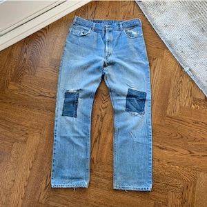 Op de afbeelding: Lichtblauwe spijkerbroek met twee donkerblauwe patches op de knieën. De spijkerbroek heeft een vervaagde look en is distressed.