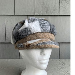 May include: A gray and white checkered newsboy cap with a brown brim. The cap is made of a soft, fuzzy material.