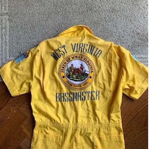 May include: Yellow short-sleeved jumpsuit with the text "West Virginia" and the state seal on the back. The text "Bassmaster" is also on the back.